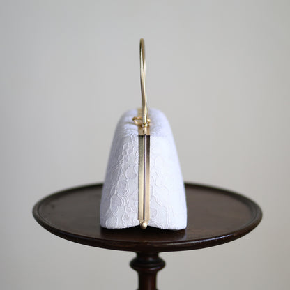 Side view of a white lace handbag